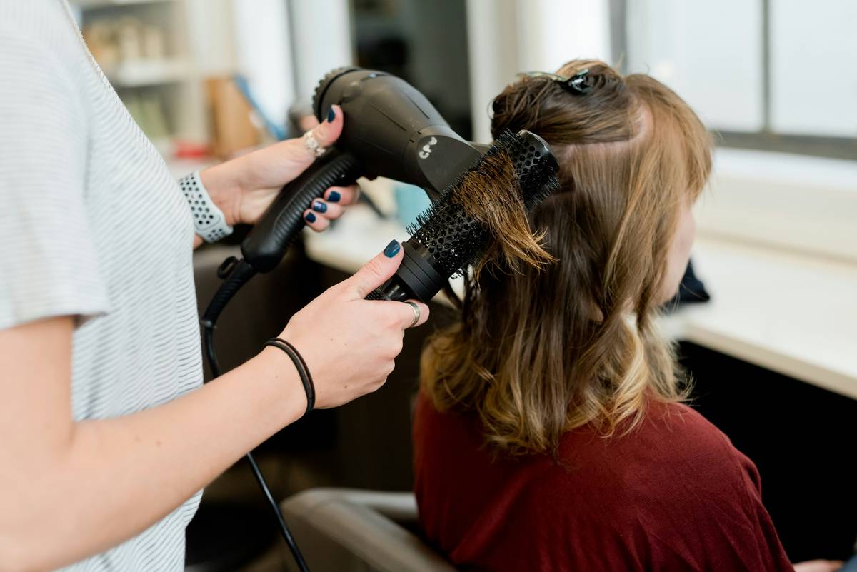 Close-up of hand applying volume hair powder to hair roots for instant lift and texture