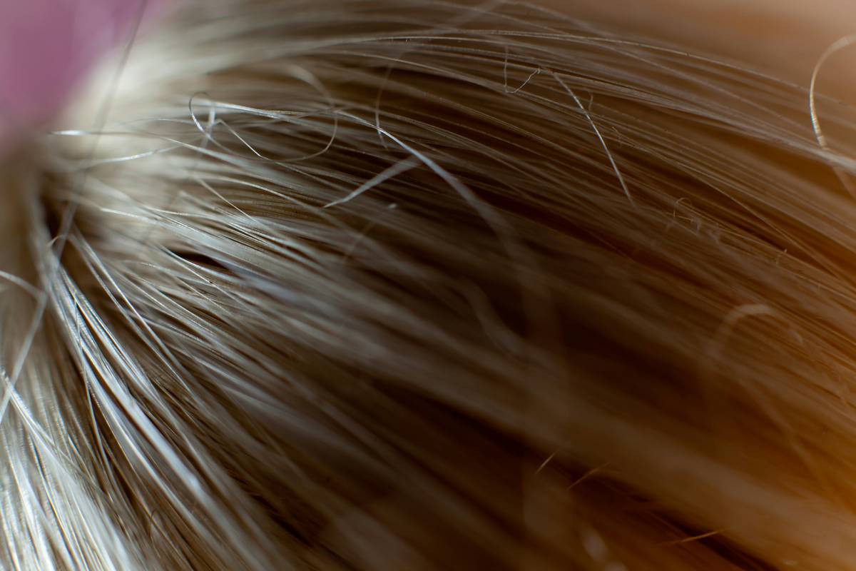 Woman applying hair conditioner to mid-lengths of thin hair to add volume and reduce breakage