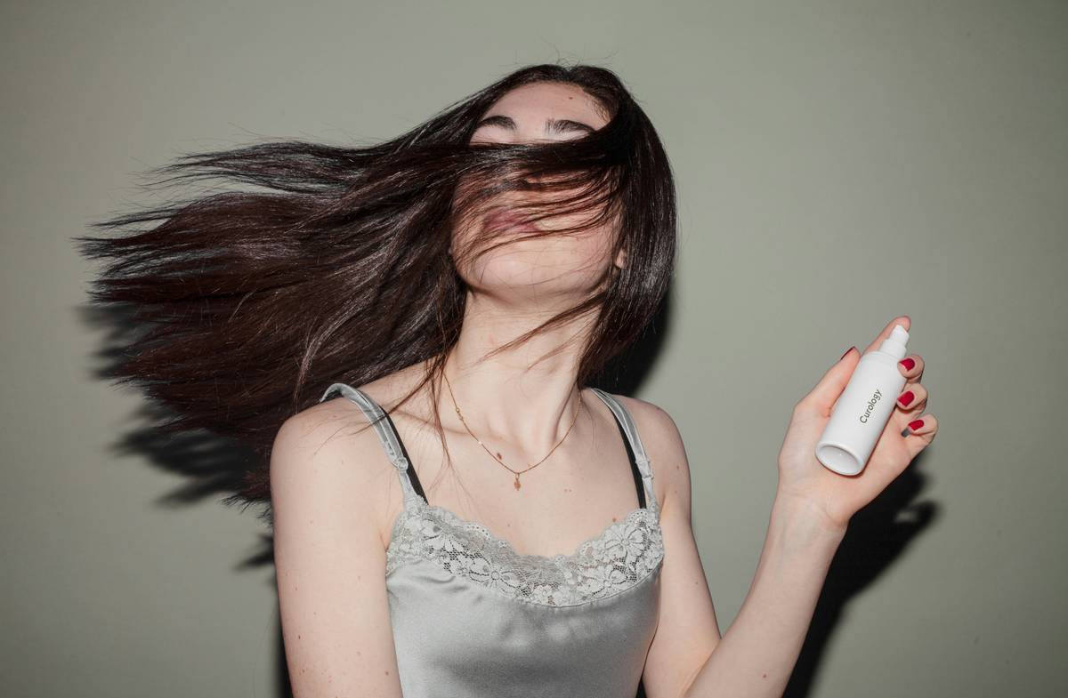 Woman applying root lift spray at the roots of her hair for instant volume